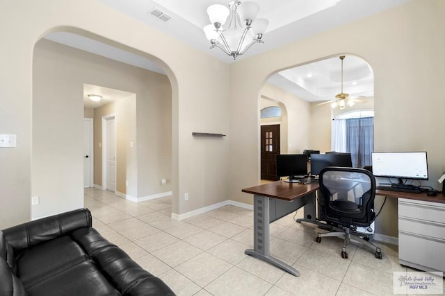 office area featuring light tile patterned floors, ceiling fan with notable chandelier, and a tray ceiling