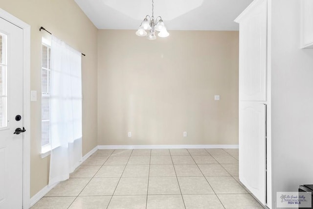 unfurnished room with a notable chandelier and light tile patterned flooring