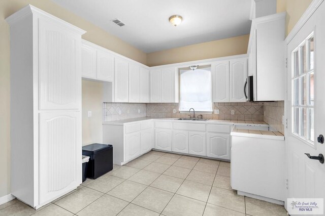 kitchen featuring white cabinetry, sink, tile countertops, decorative backsplash, and light tile patterned flooring