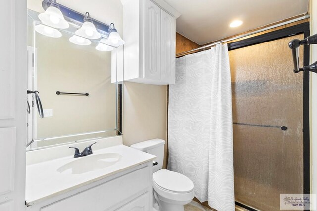 bathroom with curtained shower, vanity, and toilet