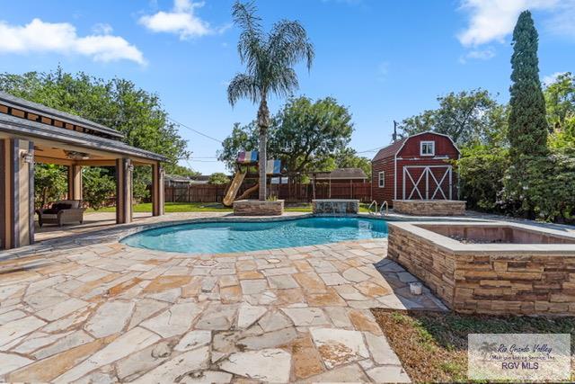 view of swimming pool with a patio area, pool water feature, and a storage shed