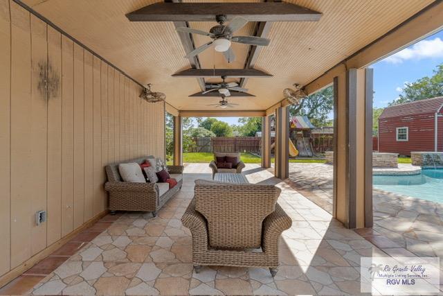 view of patio with an outdoor hangout area, pool water feature, ceiling fan, a fenced in pool, and a playground