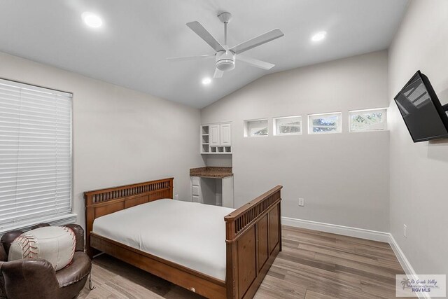 bedroom with ceiling fan, vaulted ceiling, and light wood-type flooring