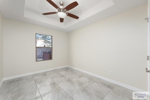 empty room featuring a tray ceiling and ceiling fan