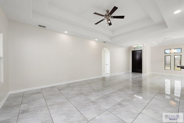 empty room featuring a tray ceiling and ceiling fan