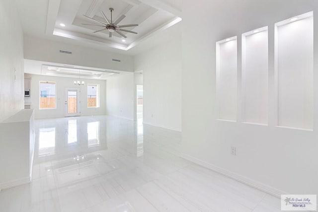 unfurnished room with baseboards, visible vents, a tray ceiling, and a ceiling fan