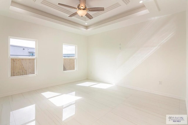 unfurnished room with ceiling fan, a tray ceiling, and baseboards