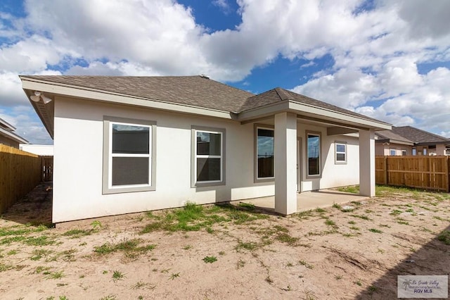 back of house featuring a patio area, a fenced backyard, a shingled roof, and stucco siding