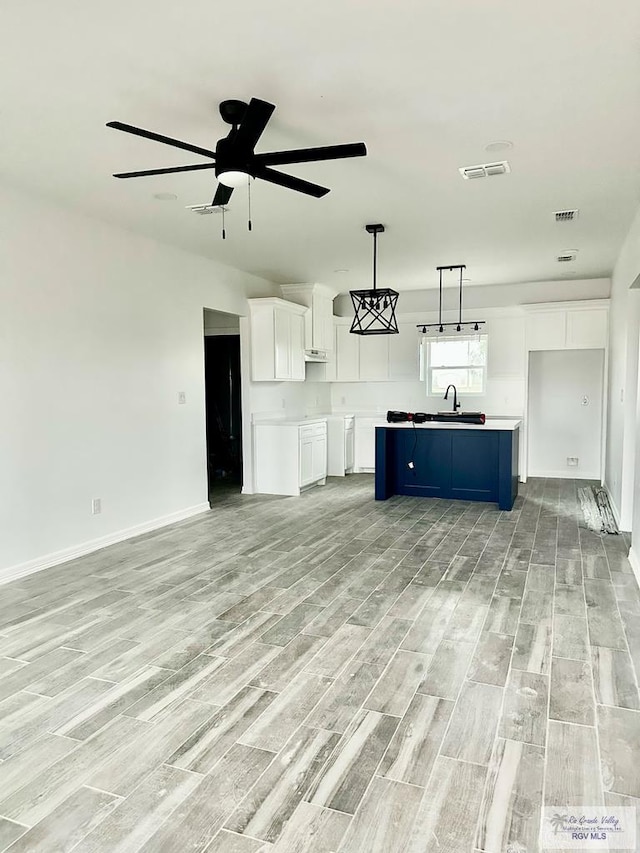 unfurnished living room featuring sink, light hardwood / wood-style floors, and ceiling fan