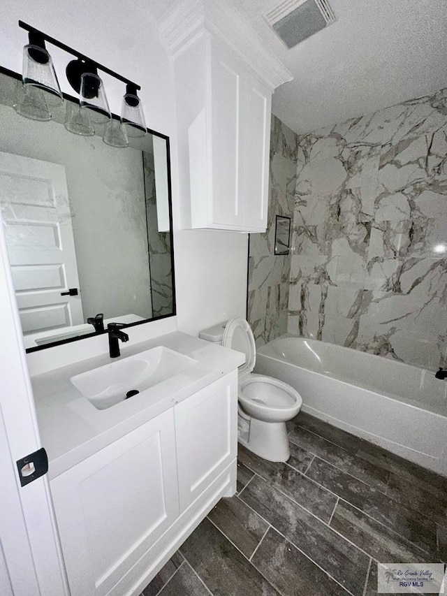 full bathroom with tiled shower / bath, vanity, toilet, and a textured ceiling