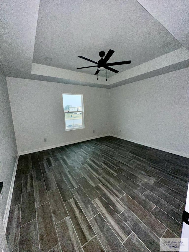 empty room with a raised ceiling, a textured ceiling, and ceiling fan