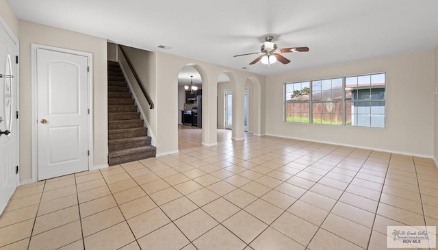2344 Munich St, Brownsville, TX 78520 - spare room featuring arched walkways, a ceiling fan, stairway, light tile patterned floors, and a chandelier