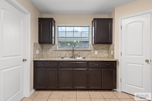 2344 Munich St, Brownsville, TX 78520 - kitchen with backsplash, dark brown cabinetry, light tile patterned floors, and light stone counters