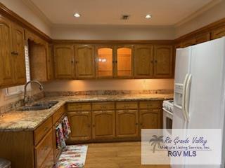 kitchen featuring light stone counters, sink, white appliances, and light hardwood / wood-style floors