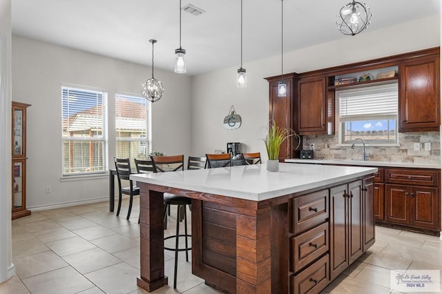 16756 E Barger Ct, Harlingen, TX 78552 - kitchen with a breakfast bar area, a sink, light countertops, tasteful backsplash, and light tile patterned flooring