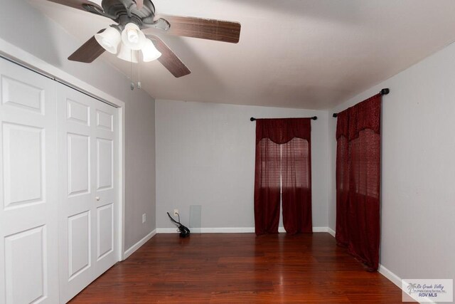 unfurnished bedroom with a closet, ceiling fan, dark hardwood / wood-style flooring, and vaulted ceiling