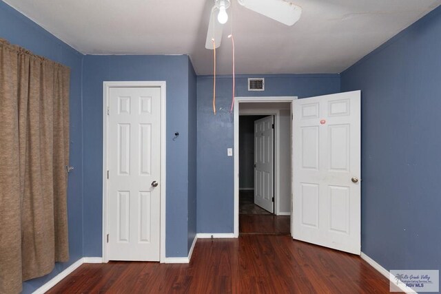 unfurnished bedroom with ceiling fan and dark wood-type flooring