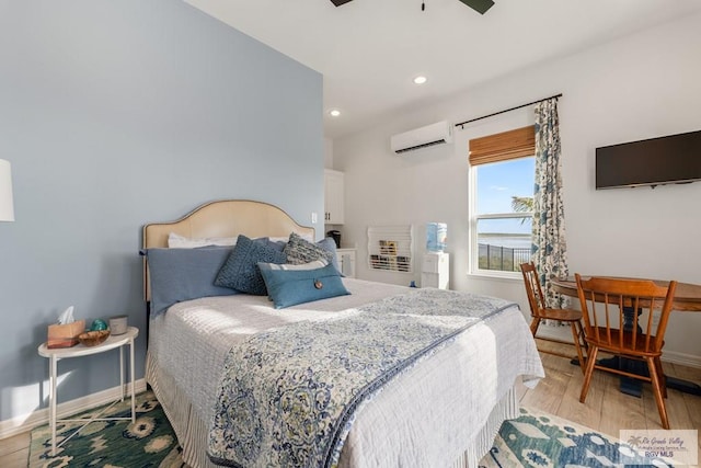 bedroom featuring a wall mounted air conditioner, ceiling fan, and light hardwood / wood-style flooring