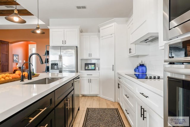 kitchen featuring white cabinets, sink, hanging light fixtures, decorative backsplash, and stainless steel appliances