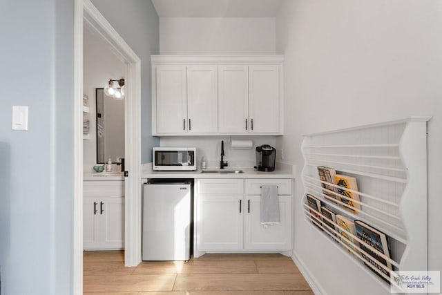 bar featuring white cabinetry, sink, and fridge