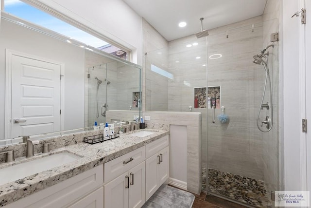 bathroom featuring a shower with shower door and vanity