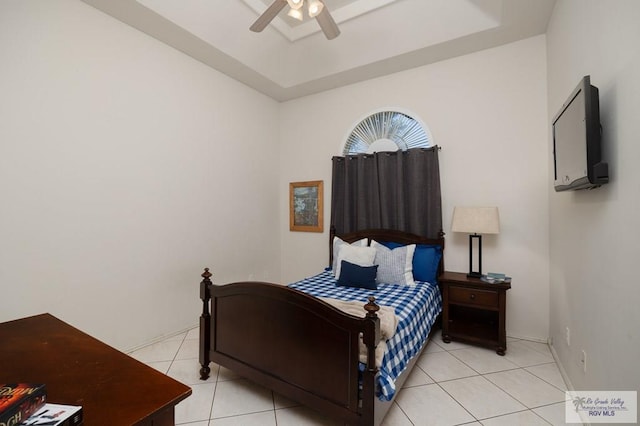 bedroom featuring light tile patterned floors, a tray ceiling, and ceiling fan