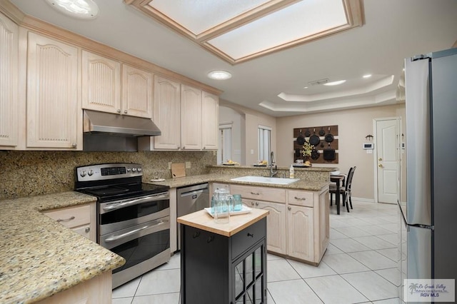 kitchen with a center island, sink, light stone counters, kitchen peninsula, and stainless steel appliances