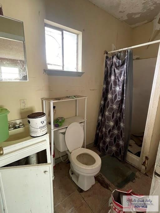 bathroom featuring tile patterned floors, toilet, walk in shower, and a wealth of natural light