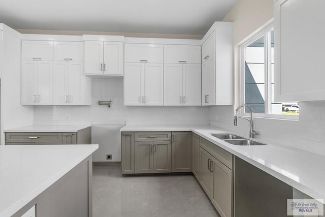 kitchen featuring white cabinetry, sink, gray cabinets, light stone counters, and decorative backsplash