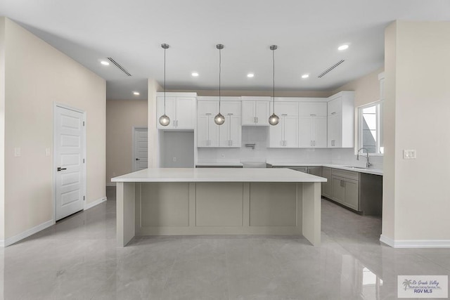 kitchen with sink, white cabinets, a center island, and pendant lighting