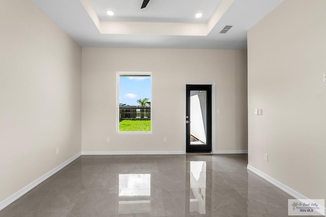 spare room featuring a tray ceiling and ceiling fan