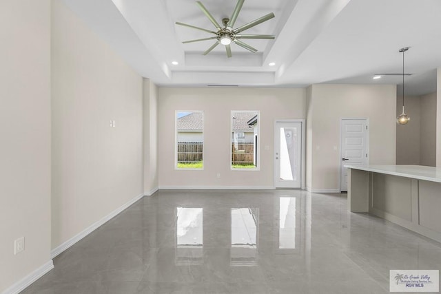 unfurnished living room featuring a raised ceiling and ceiling fan