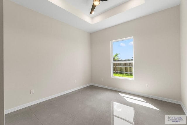 spare room with ceiling fan and a raised ceiling