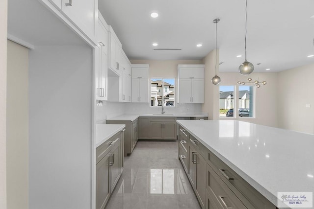 kitchen featuring tasteful backsplash, white cabinets, decorative light fixtures, gray cabinets, and sink