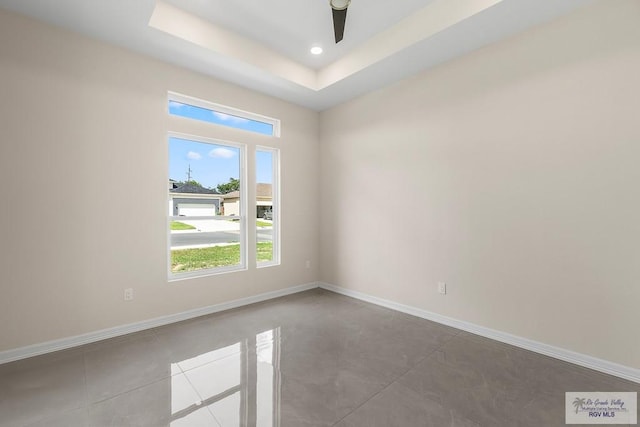 empty room with a raised ceiling and ceiling fan