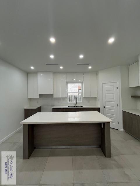 4031 Tito Ct Unit 45, Brownsville, TX 78521 - kitchen with white cabinets, a sink, a kitchen island, baseboards, and recessed lighting