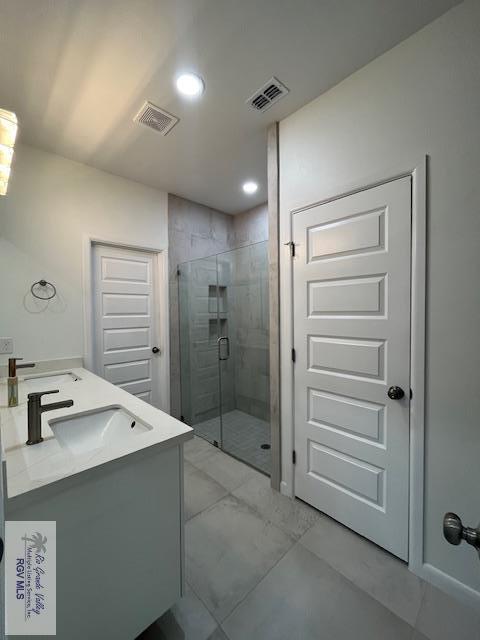 4031 Tito Ct Unit 45, Brownsville, TX 78521 - bathroom with visible vents, a shower stall, double vanity, and a sink