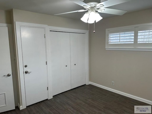 unfurnished bedroom featuring dark wood-type flooring, ceiling fan, and a closet