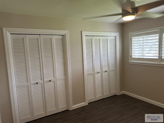 unfurnished bedroom featuring multiple closets, ceiling fan, and dark hardwood / wood-style flooring