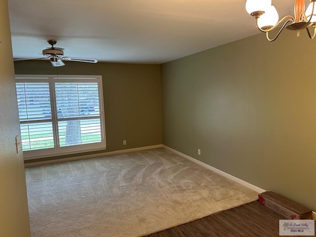 spare room featuring wood-type flooring and ceiling fan with notable chandelier