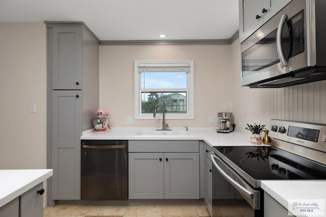 1215 Bluebonnet Dr, Brownsville, TX 78521 - kitchen featuring stainless steel appliances, gray cabinetry, a sink, light countertops, and ornamental molding