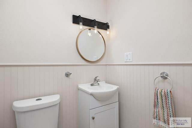 1215 Bluebonnet Dr, Brownsville, TX 78521 - bathroom with a wainscoted wall, vanity, and toilet