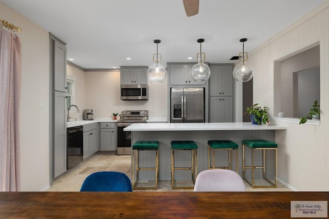 1215 Bluebonnet Dr, Brownsville, TX 78521 - kitchen featuring stainless steel appliances, gray cabinetry, a kitchen bar, a peninsula, and light countertops