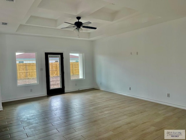 empty room with beam ceiling, coffered ceiling, ceiling fan, and light hardwood / wood-style flooring