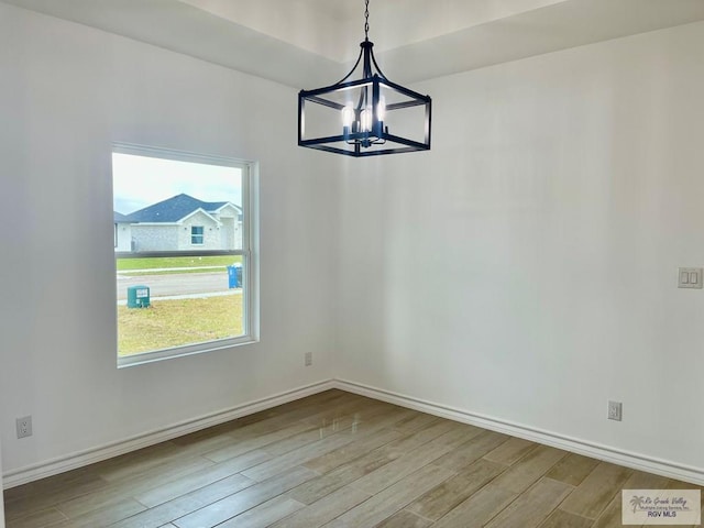 unfurnished dining area with an inviting chandelier and light hardwood / wood-style flooring