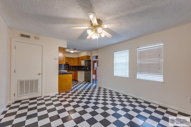115 E Armstrong Ct, Brownsville, TX 78521 - kitchen featuring dark floors, brown cabinetry, ceiling fan, dark countertops, and a textured ceiling