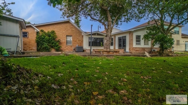 115 E Armstrong Ct, Brownsville, TX 78521 - rear view of property featuring brick siding, a lawn, and cooling unit