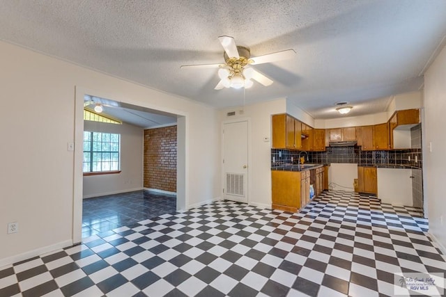 115 E Armstrong Ct, Brownsville, TX 78521 - kitchen with brown cabinets, tile patterned floors, a ceiling fan, decorative backsplash, and under cabinet range hood