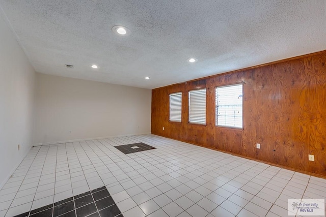 115 E Armstrong Ct, Brownsville, TX 78521 - tiled spare room featuring wooden walls, recessed lighting, baseboards, and a textured ceiling