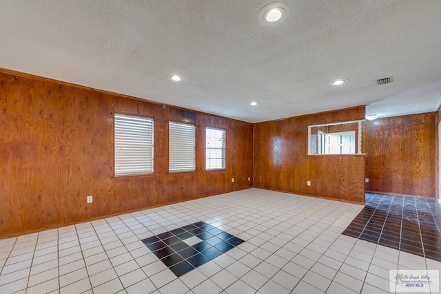 115 E Armstrong Ct, Brownsville, TX 78521 - empty room with wood walls, healthy amount of natural light, light tile patterned floors, recessed lighting, and a textured ceiling